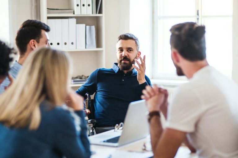 Hombres y mujeres discutiendo en una reunión en una oficina iluminada.