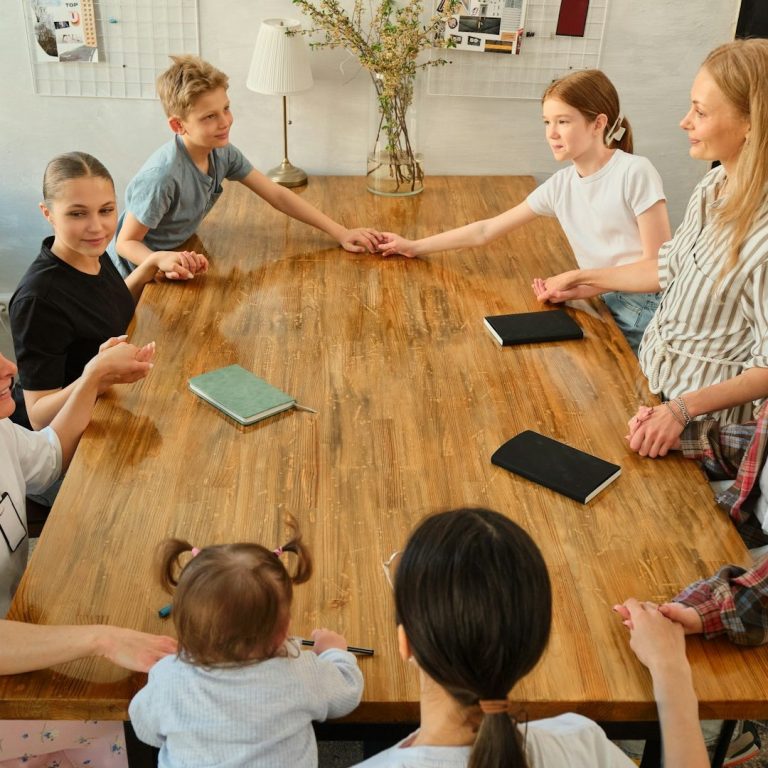 Conversando en la mesa Grupo de personas sentadas alrededor de una mesa, interactuando y conversando.