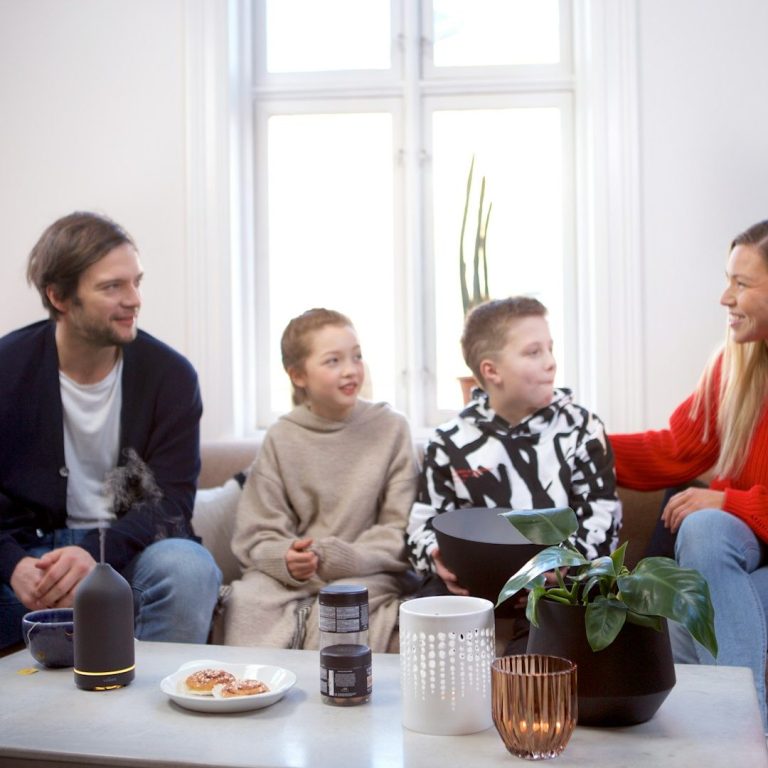 Familia Familia sentada en un sofá, conversando y sonriendo en un ambiente acogedor.